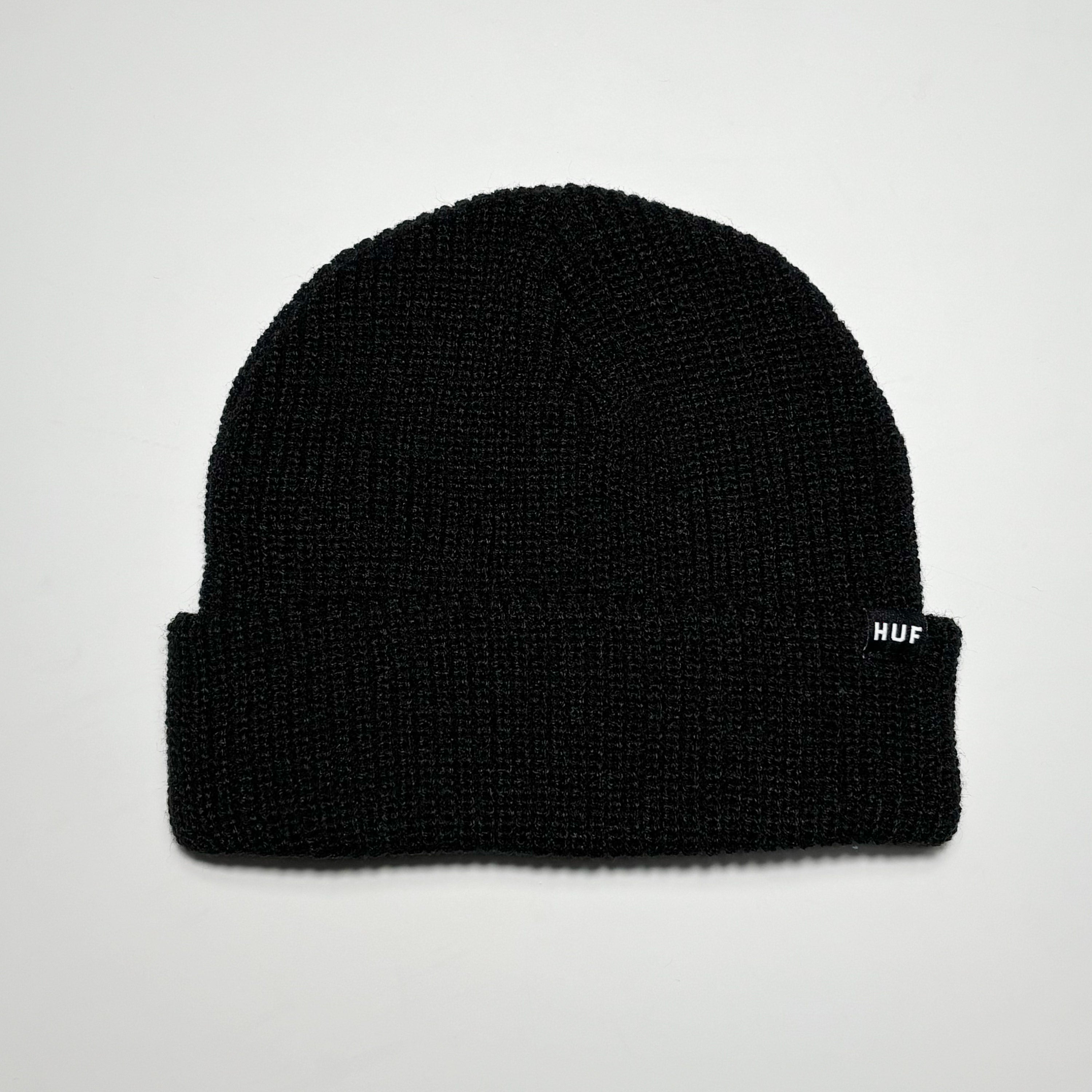 Black knit beanie with woven HUF label on fold.