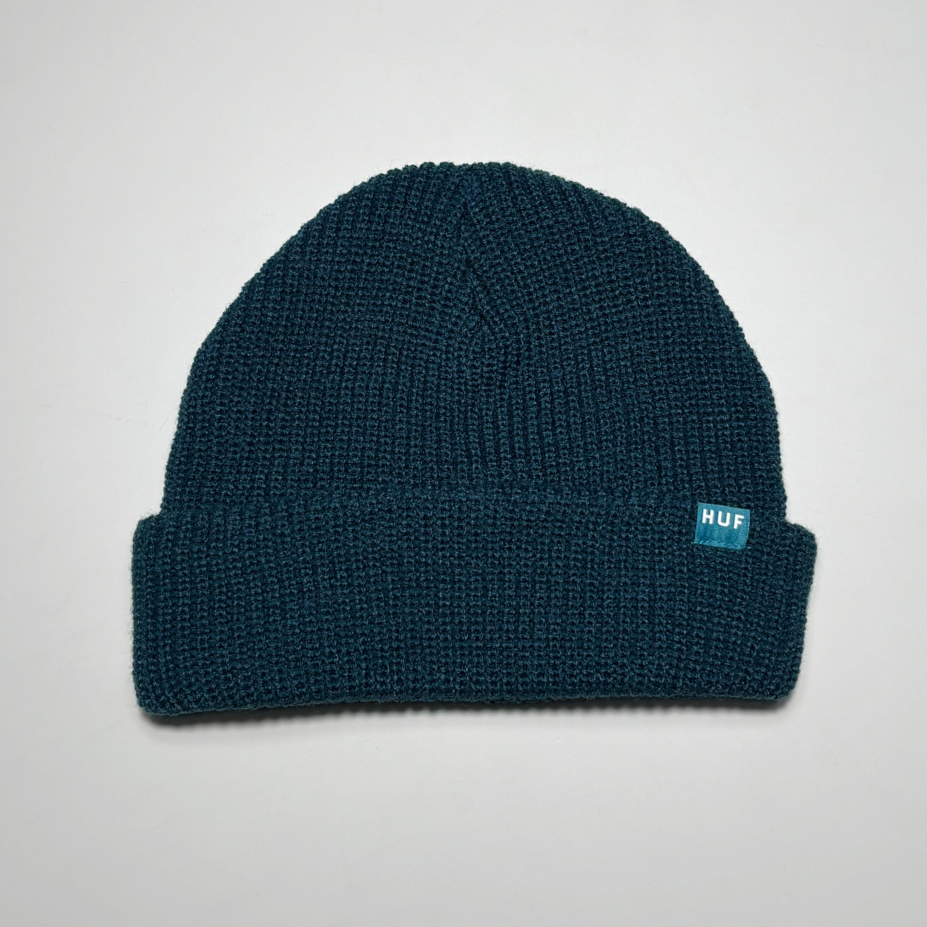 Dark blue knit beanie with woven HUF label on fold. 
