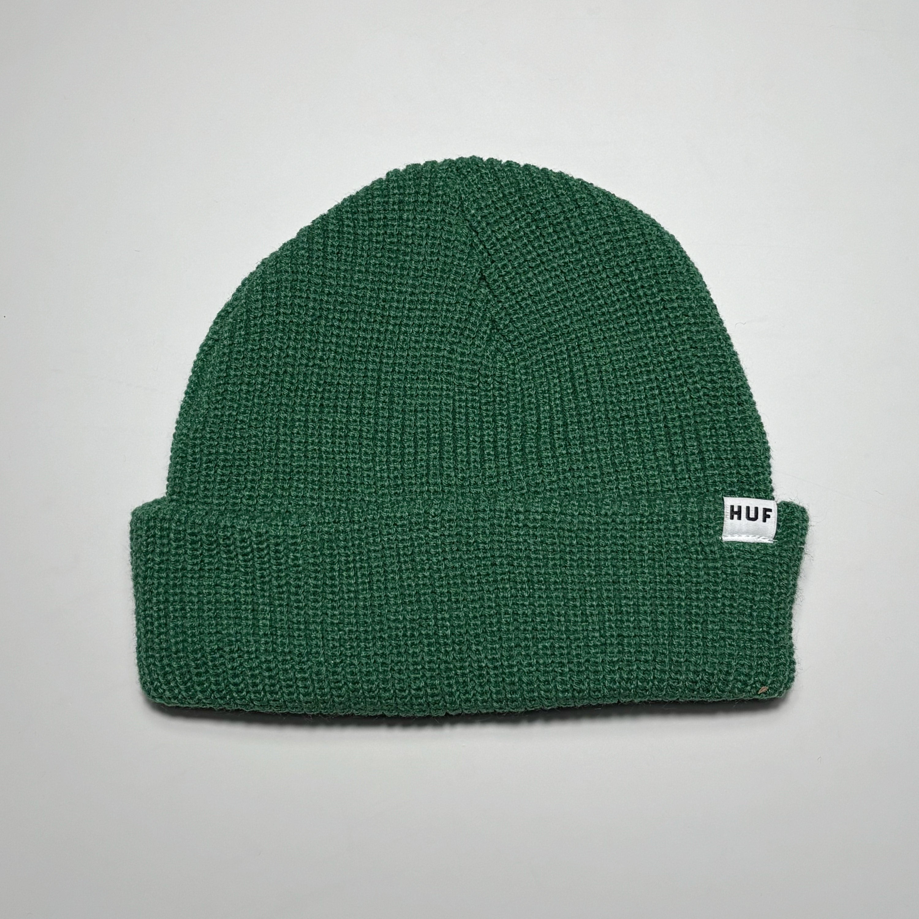 Green knit beanie with woven HUF label on fold.