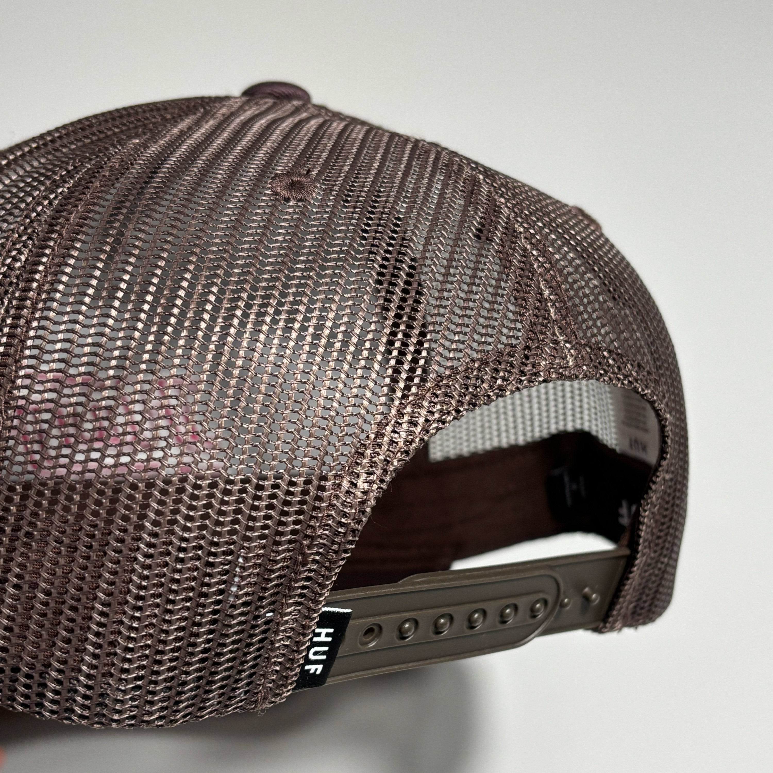 back detail of brown mesh cap with HUF label on back.