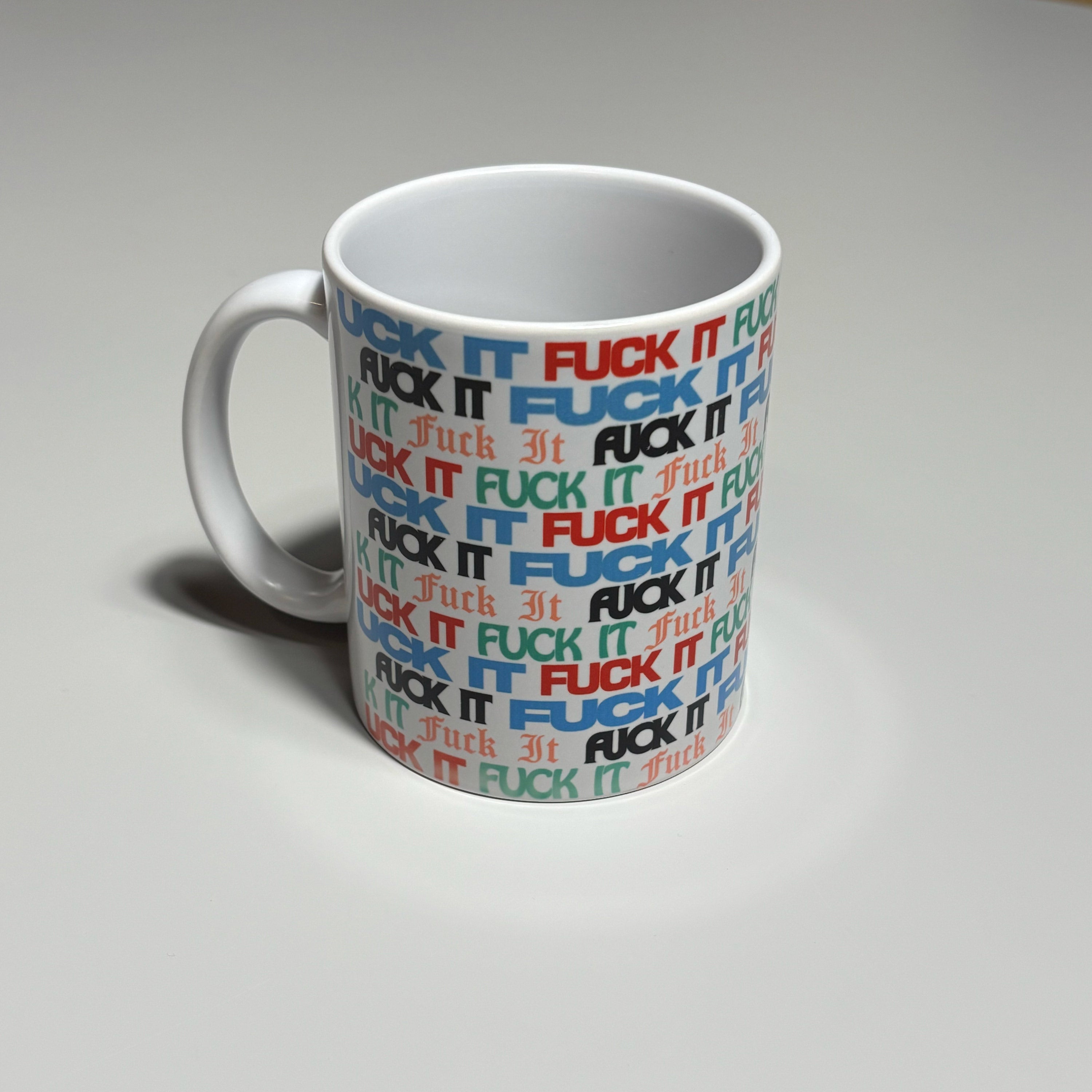 White mug with colorful 'FUCK IT' text pattern on a gray background