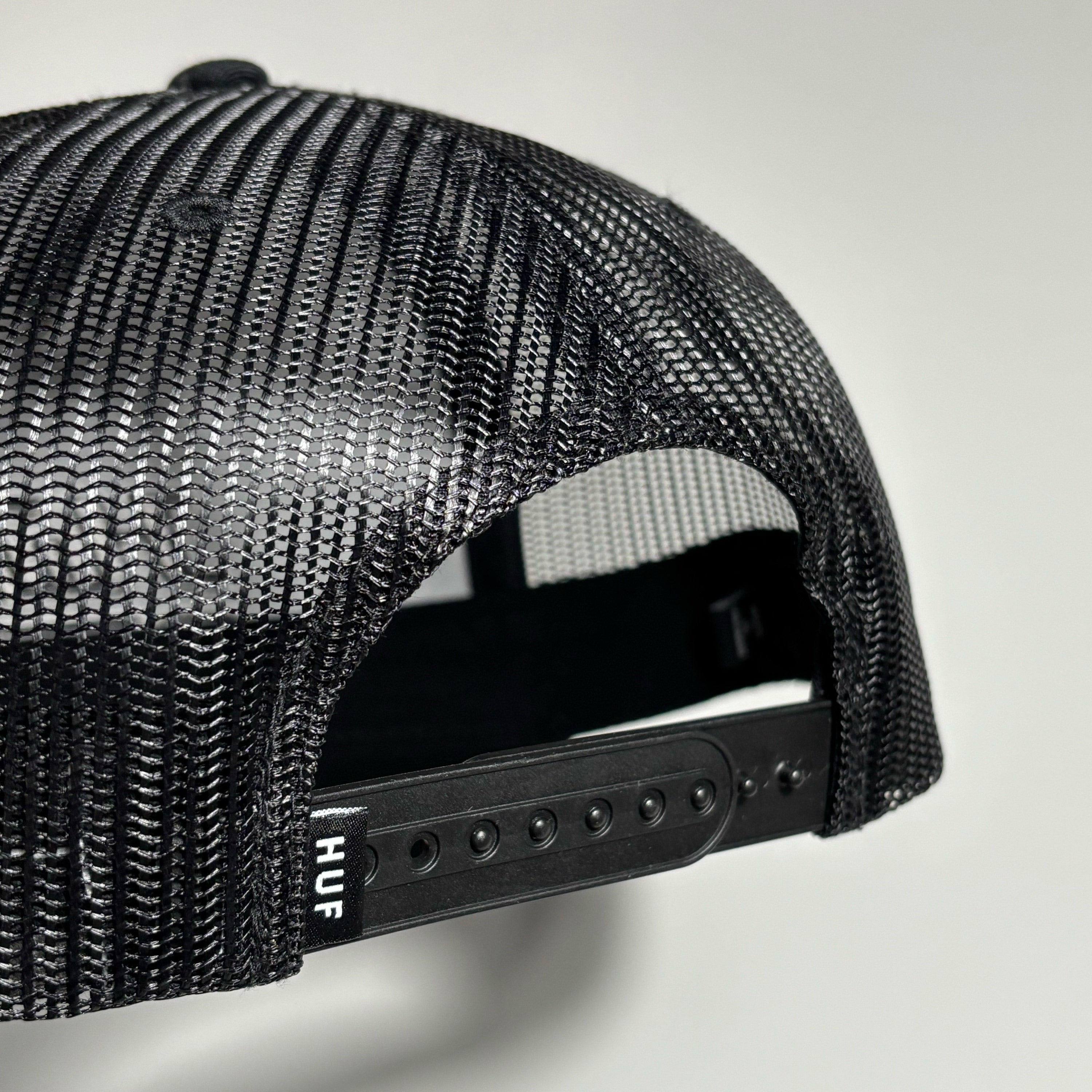 back detail of black mesh cap with HUF label on back.