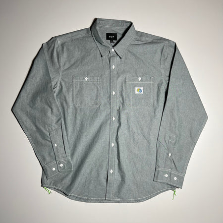 FRONT FACING CHAMBRAY DRESS SHIRT IN LIGHT BLUE WITH WHITE CONTRAST STITCHING. TWO FRONT FACING POCKETS AND HUF ECLIPSE LOGO PATCH RIGHT SIDE CHEST.