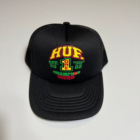 FRONT FACING BLACK TRUCKER HAT. HUF ONE CHAMPION SOUND GRAPHIC PRINTED IN YELLOW RED AND GREEN CENTER 