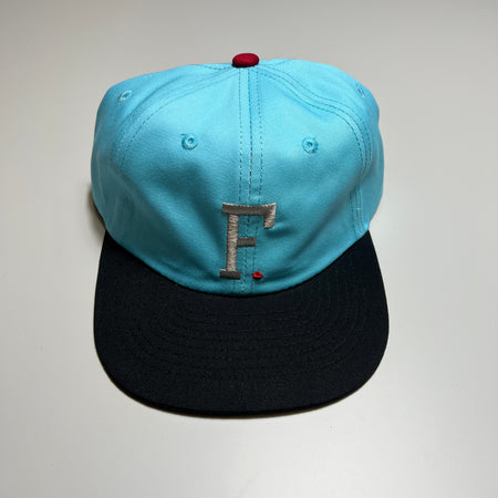 Full image of blue at with black bill. Silver embroidered "F" on crown.