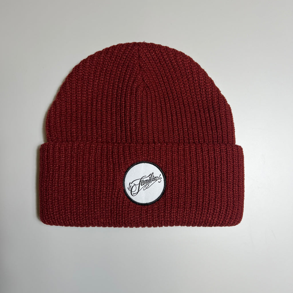 Maroon colored beanie with white and black familia script patch.