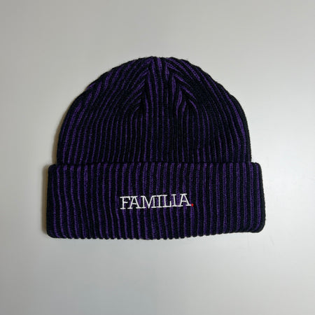 Font facing black and purple striped beanie with familia type logo embroidered in white with red dot. 