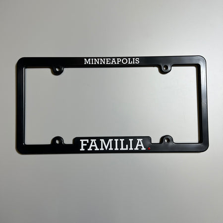 Black plastic license plate cover with minneapolis and familia printed top and bottom.