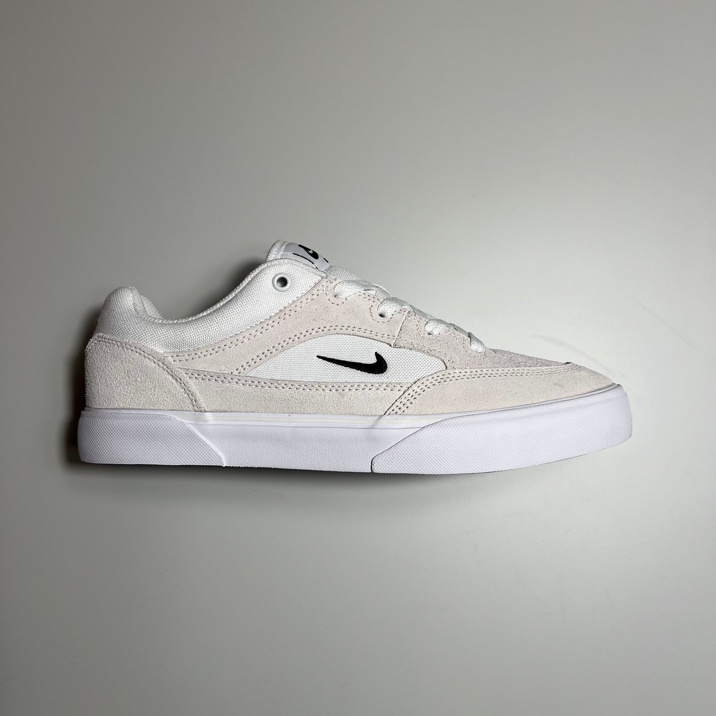 Side view of the Nike SB Malor in summit white with black embroidered check logo and white gum sole.