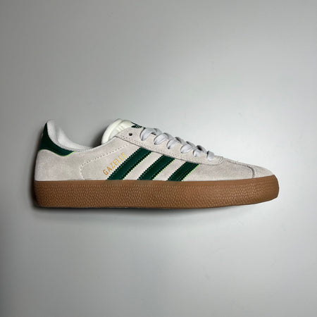 SIDE VIEW ADIDAS GAZELLE ADV IN CRYSTAL WHITE SUEDE, GREEN LEATHER STRIPES AND HEEL TAB WITH GUM SOLE.