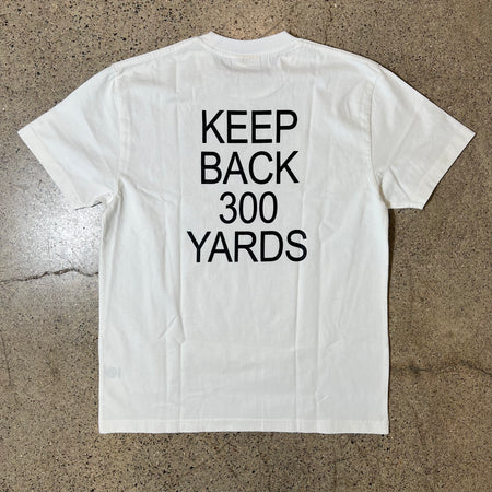 WHITE TEE WITH "KEEP BACK 300 YARDS" PRINTED ON THE BACK IN BLACK