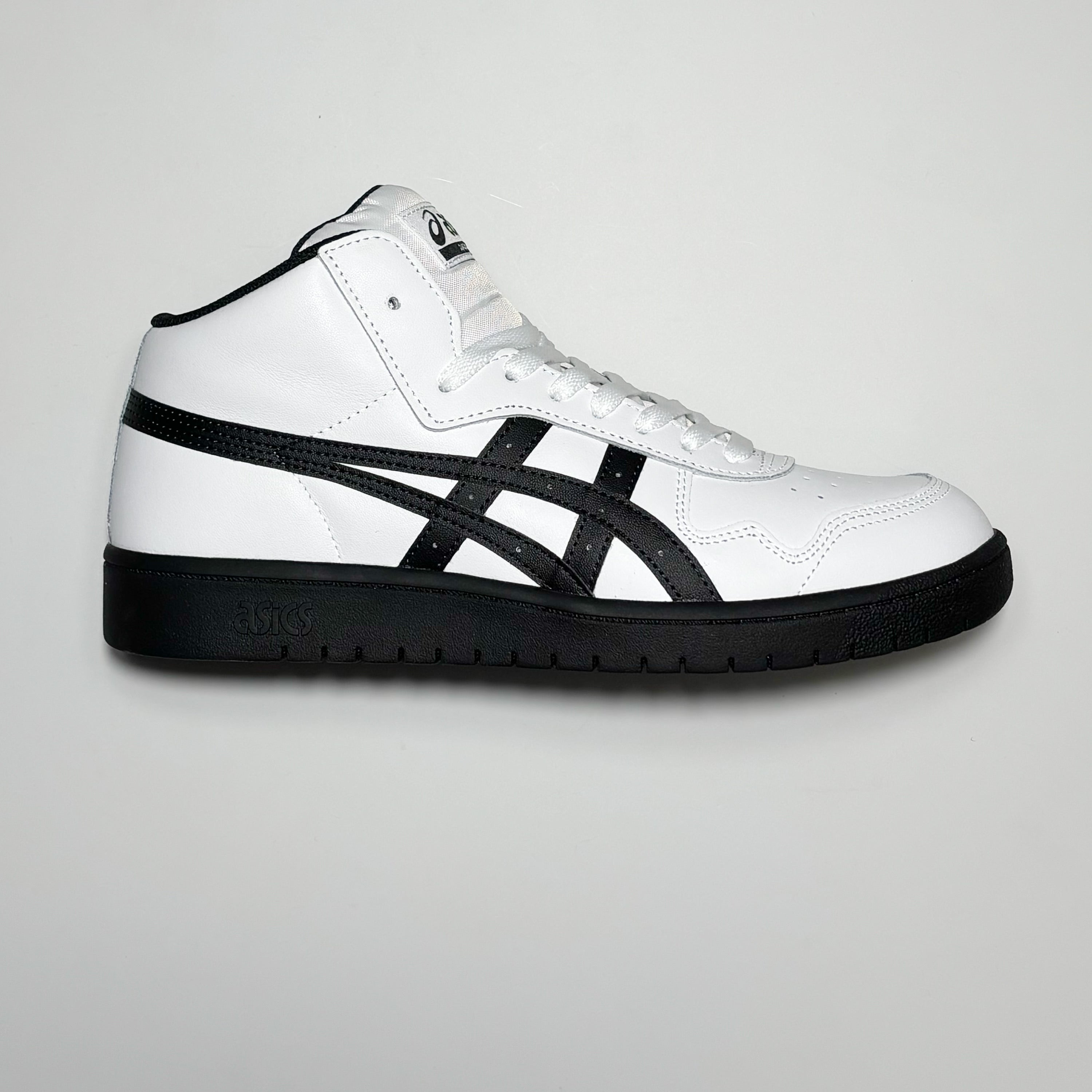 Side image of right shoe. White leather with black logo stripes and outsole.