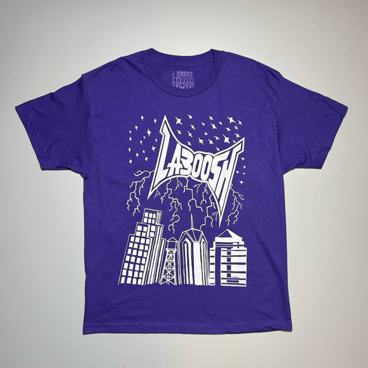 A purple short-sleeve t-shirt with a white graphic print featuring the word 'LABoosh' in a stylized font above a city skyline and lightning design, laid flat on a light gray background.