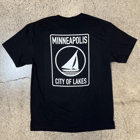 BLACK SIDE OF BLACK T-SHIRT WITH WHITE GRAPHIC OF A SAILBOAT THAT SAYS MINNEAPOLIS CITY OF LAKES