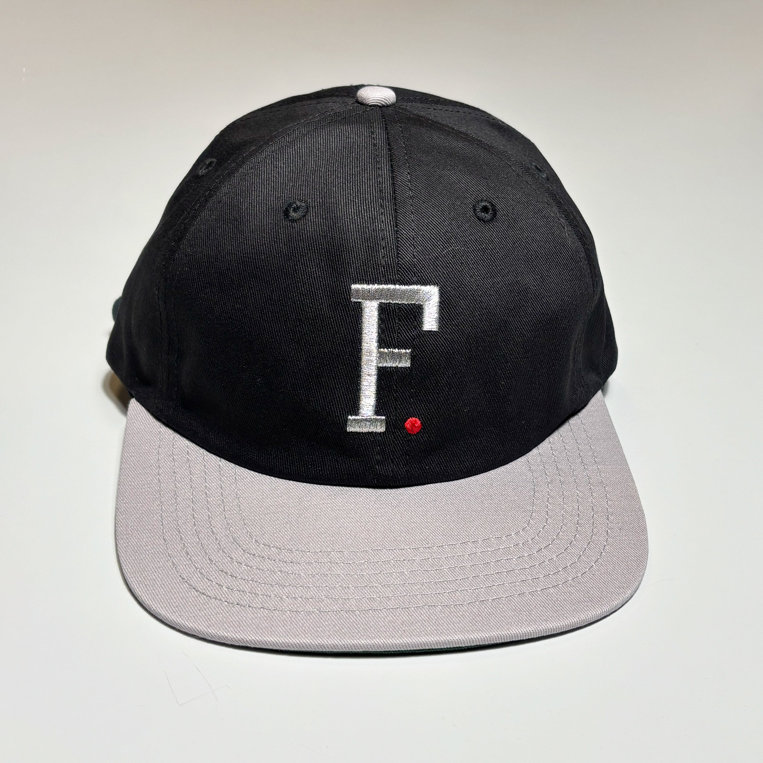 Full image of black hat with grey bill.
Metallic embroidered F on crown.