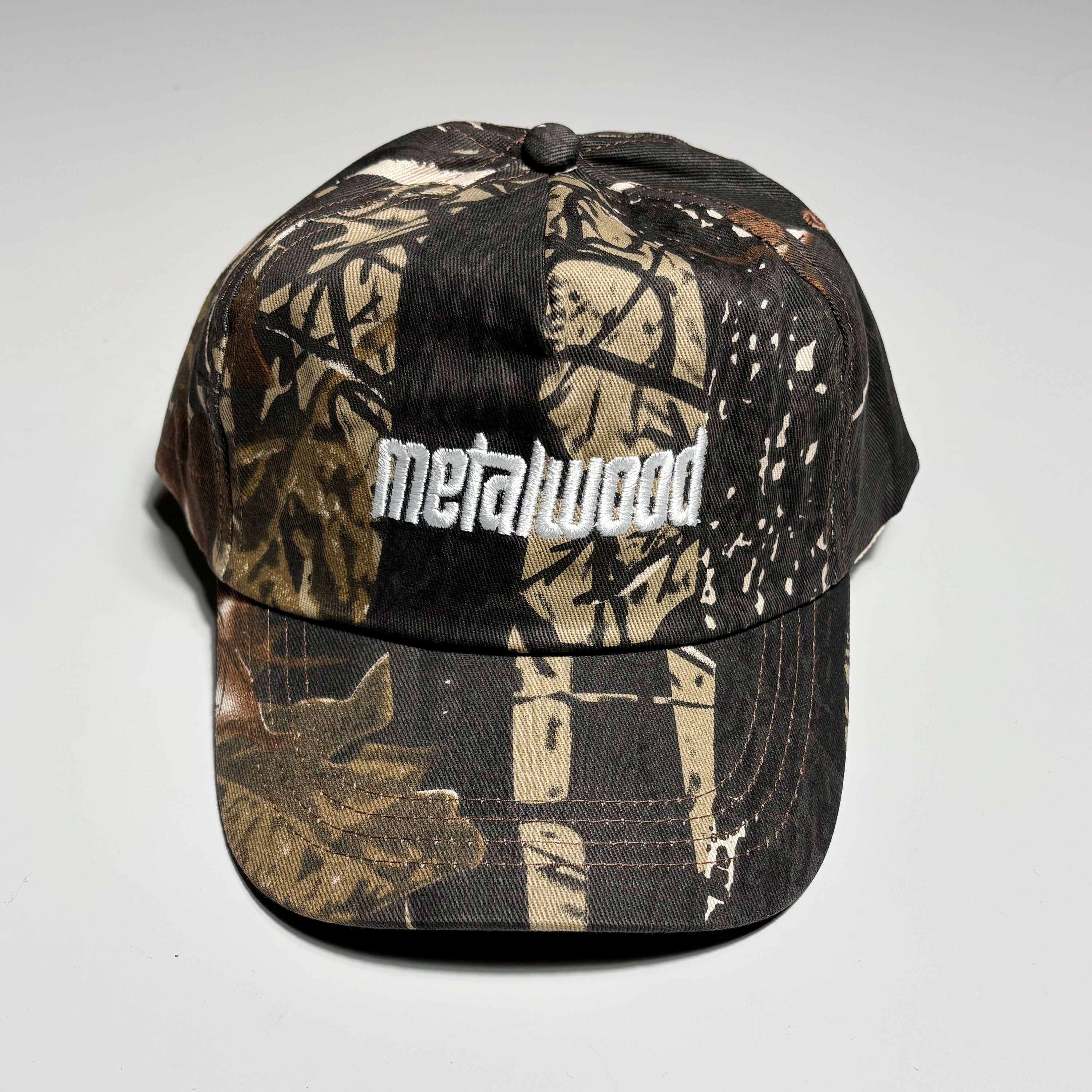 Front image of leaf camo hat with white embroidered logo on crown