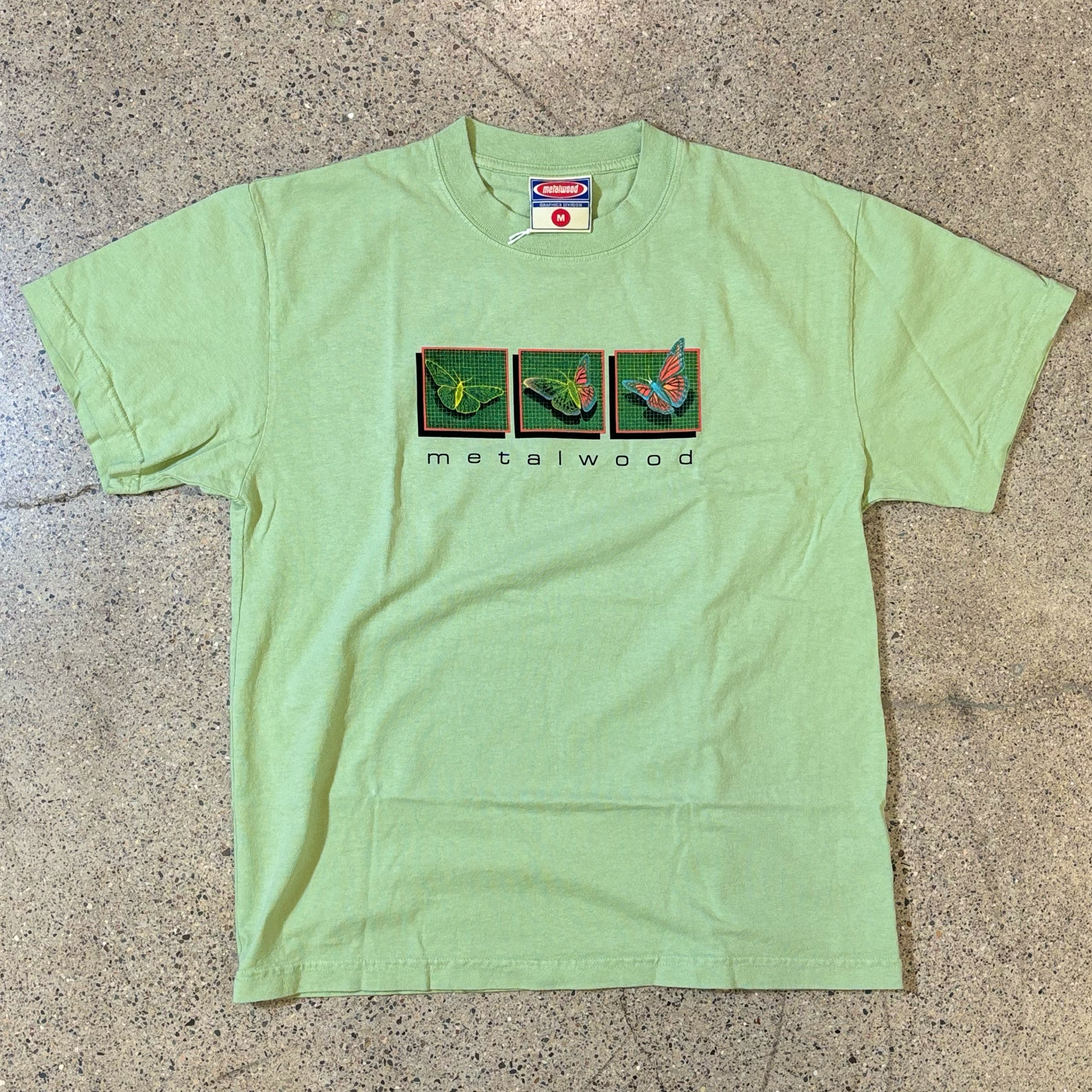 LIGHT GREEN T-SHIRT WITH THREE BUTTERFLY GRAPHIC AND BLACK METALWOOD FONT ON THE CHEST