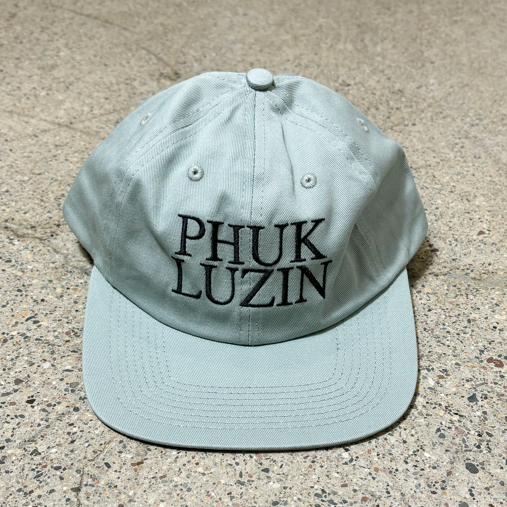 Front image of 6-panel unstructured hat with phuk luzin embroidered on crown