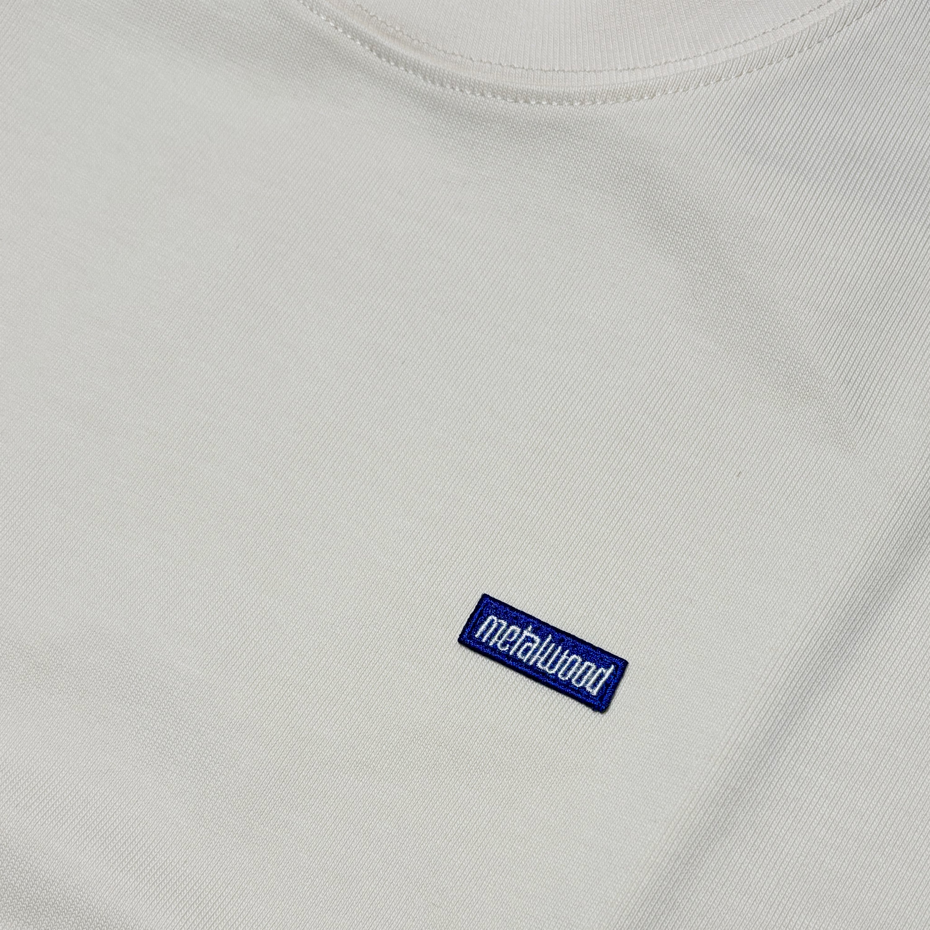 Close detail of blue embroidered label on chest.