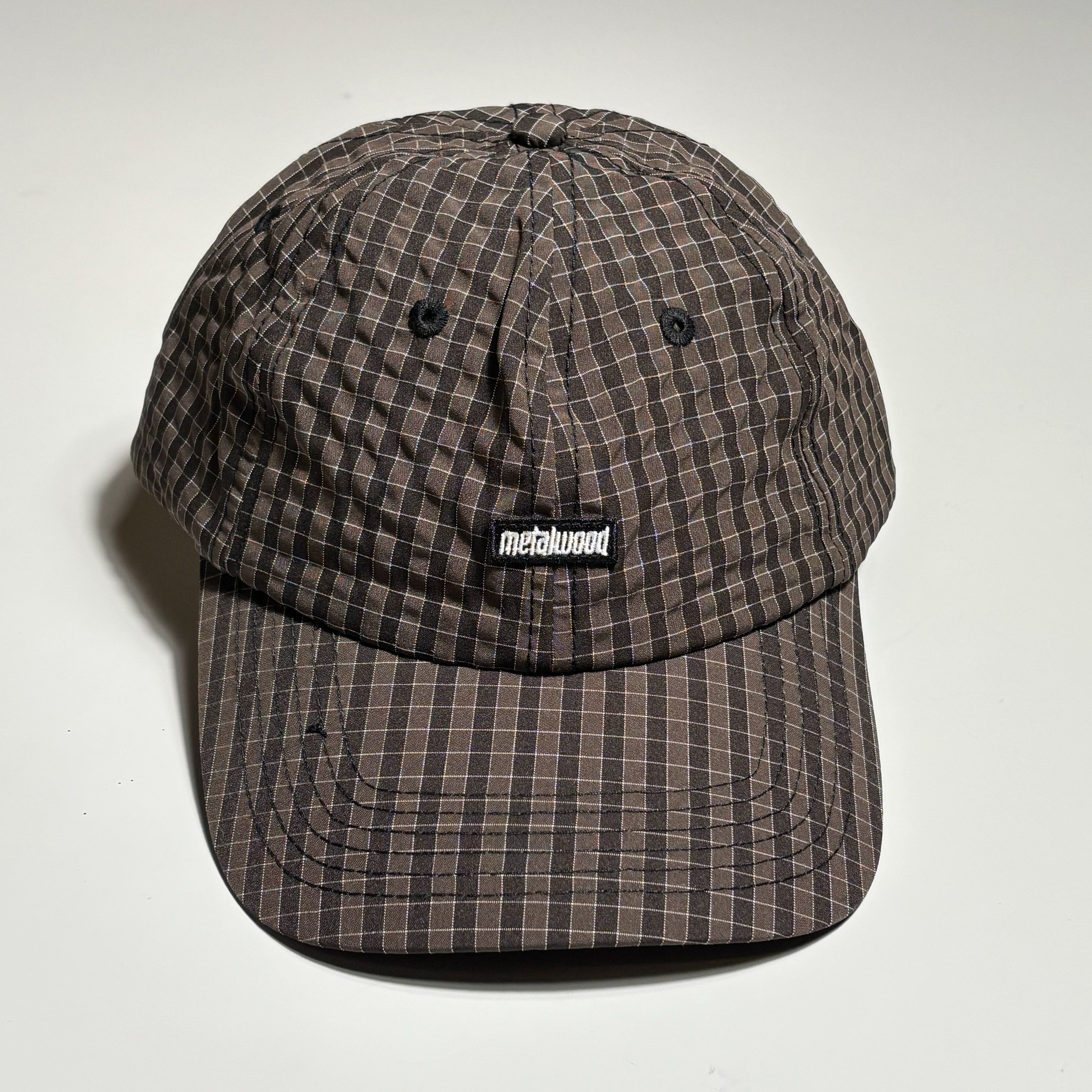 Front image of plaid hat with woven label on crown.