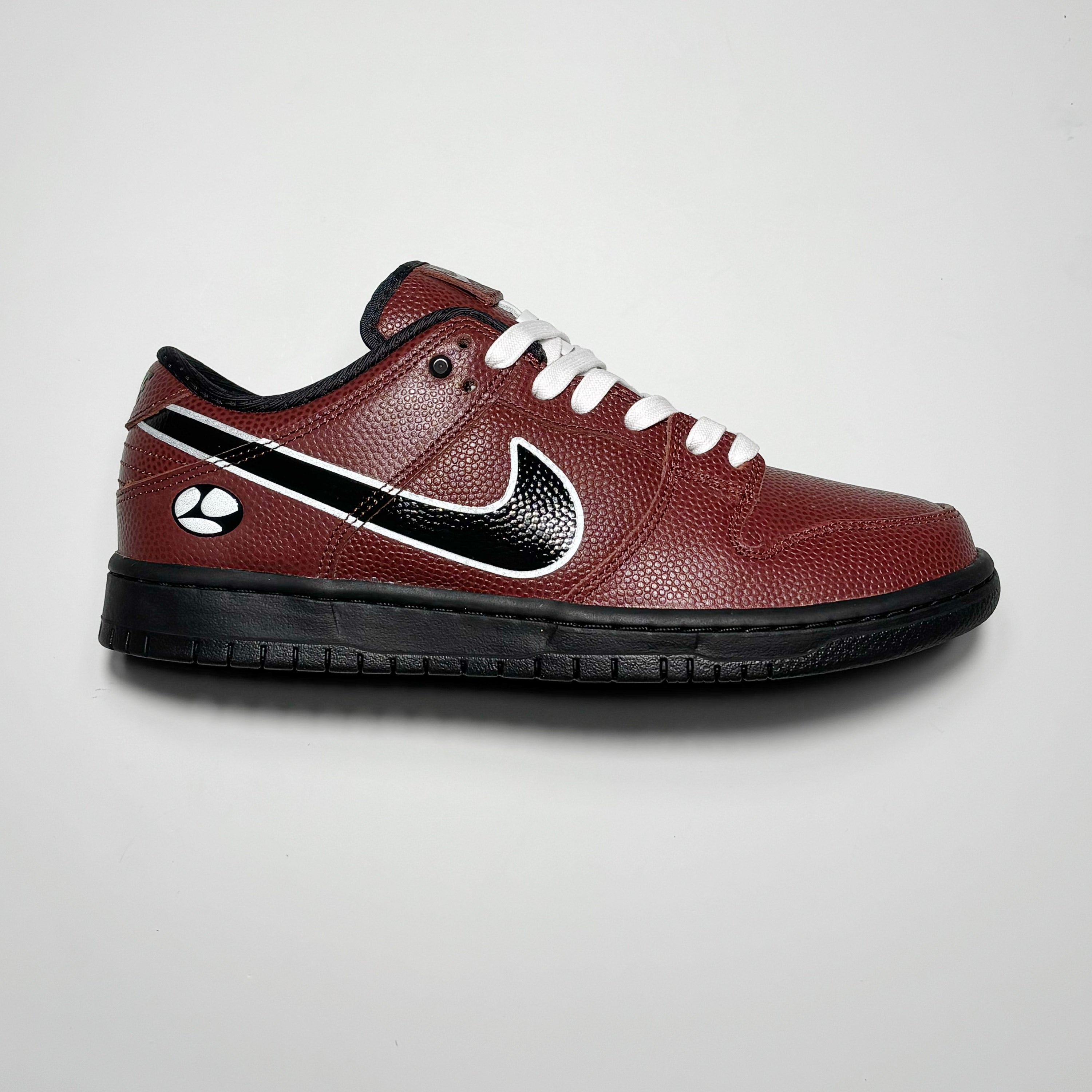Side image of right shoe. Football textured leather with printed nike swoosh and black midsole.