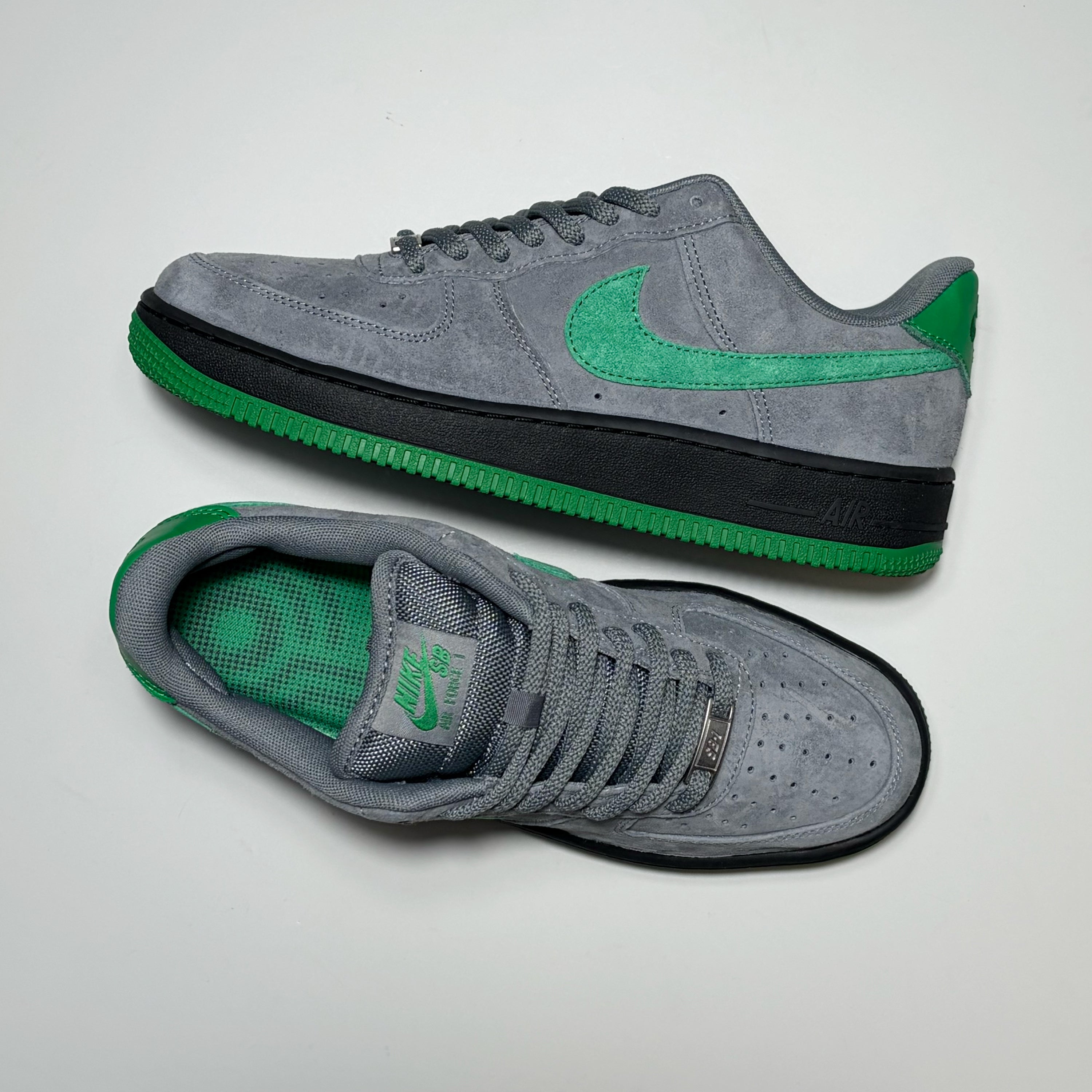 A pair of Nike SB Air Force 1 Low sneakers in gray suede with vibrant green accents and a black midsole, displayed on a light gray background.