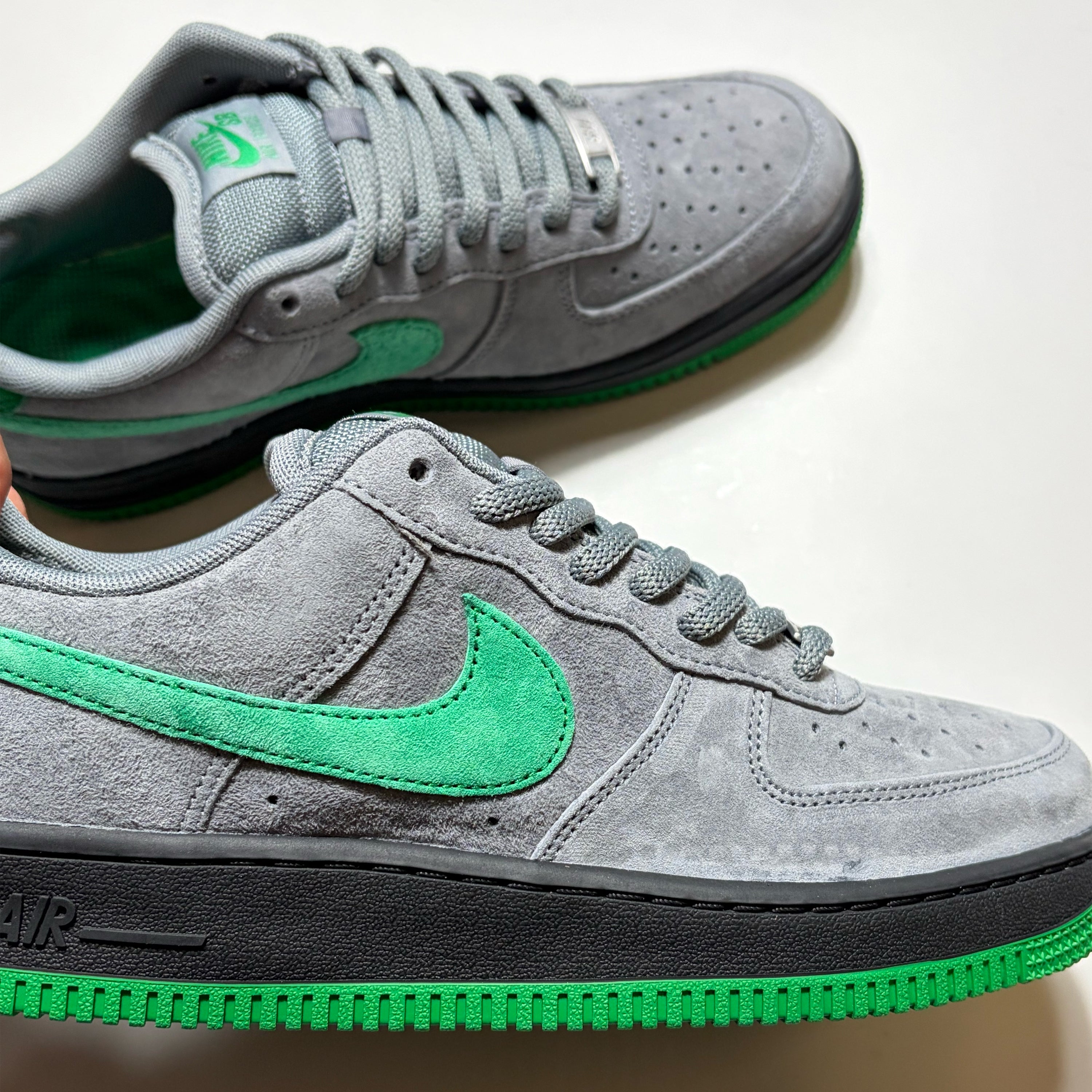 A pair of Nike SB Air Force 1 Low sneakers in gray suede with vibrant green accents, including the Swoosh, tongue, and outsole, displayed on a clean white background.