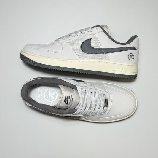 A pair of Nike SB Air Force 1 Low Yuto Horigome sneakers in white and dark gray, featuring a white leather upper, dark gray Swoosh and collar, and a cream-colored midsole.