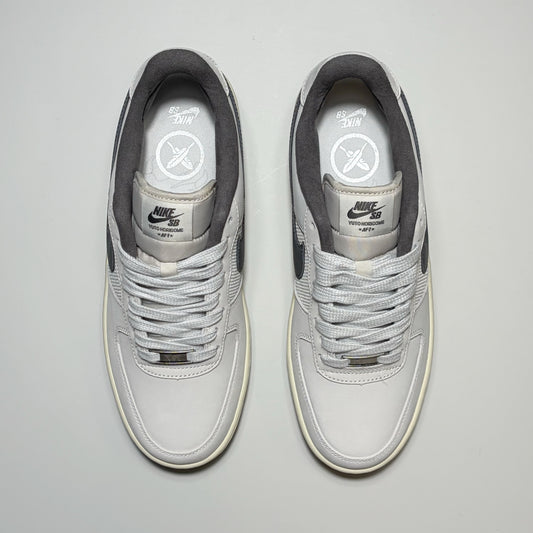 A pair of Nike SB Air Force 1 Low sneakers in light gray and white, shown from a top-down view on a light gray background.