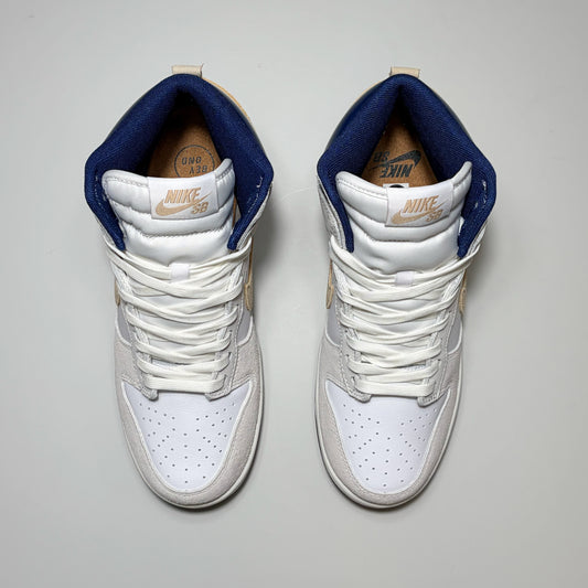 A pair of Nike SB Dunk High Pro in white, navy blue, and beige, shown from a top-down view on a light gray background.