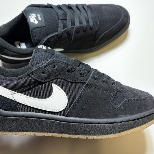 A pair of Nike SB Code 58 sneakers in black, featuring a black suede and mesh upper with a prominent white Swoosh on the side and a light beige gum sole.