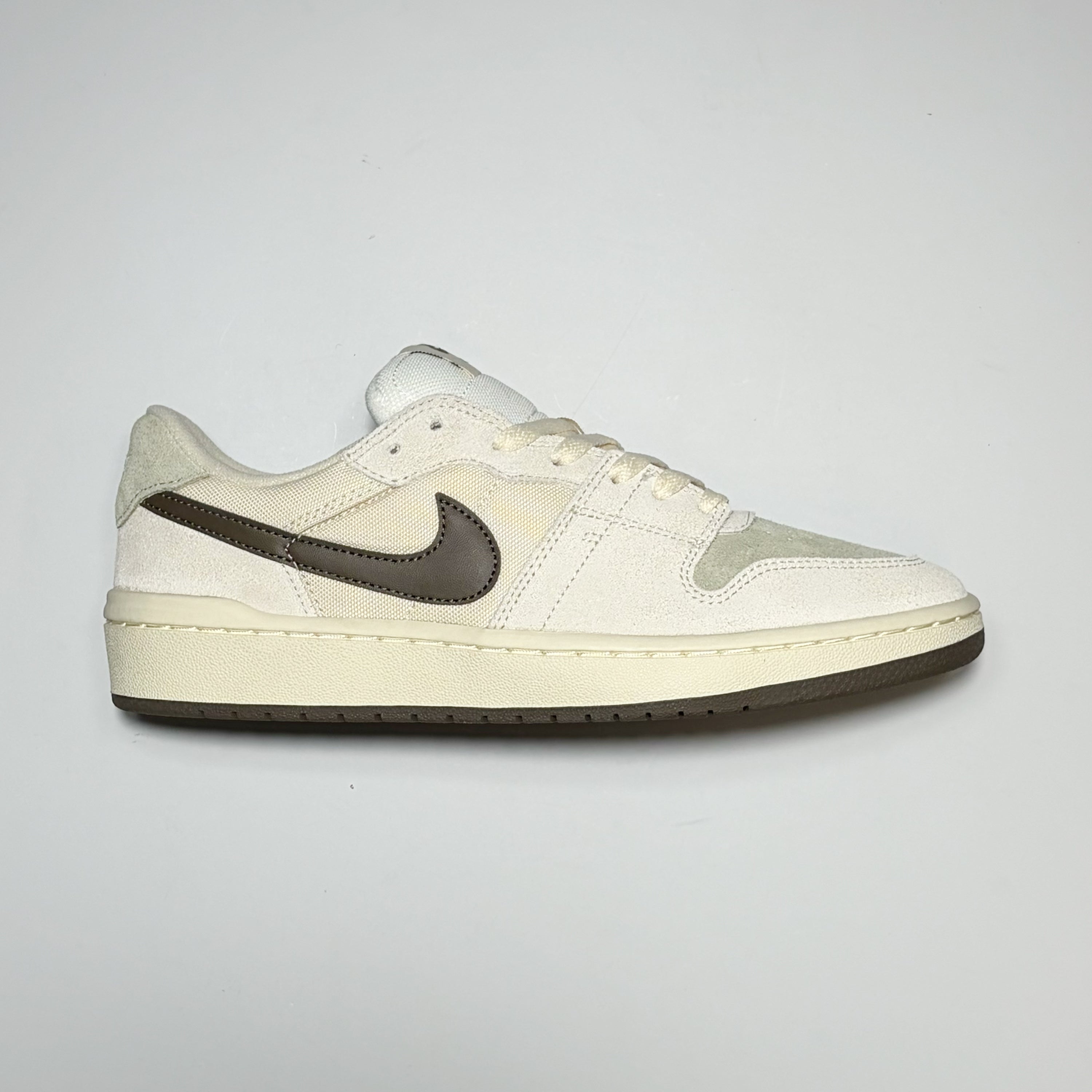 Right side image, Nike SB Code 58 shoe. Ivory white with green toe box and brown swoosh and bottom outsole.