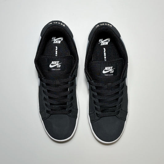 A pair of Nike SB Tennis Classic Low sneakers in black with white accents, shown from a top-down view on a light gray background.