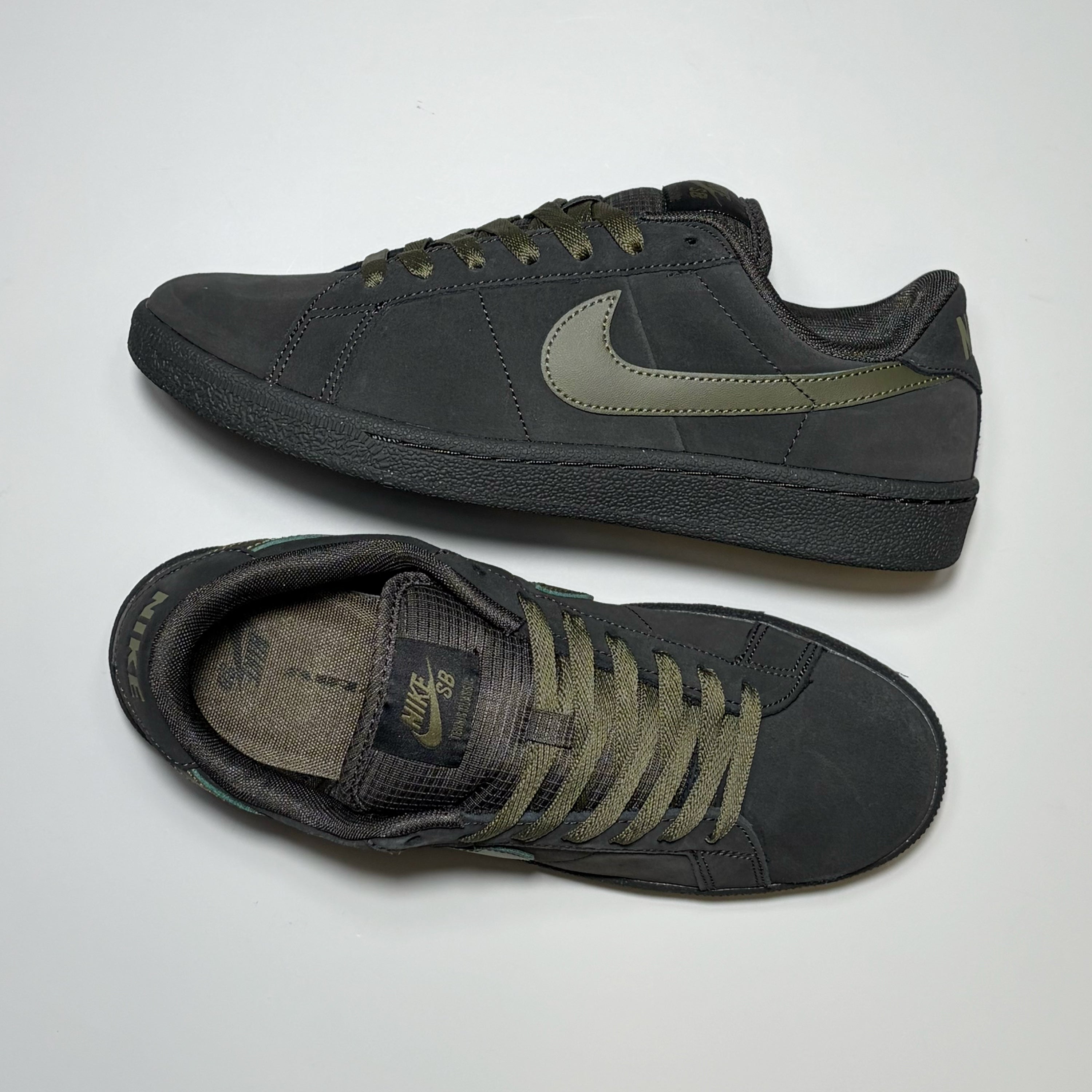 A pair of Nike SB low-top Tennis Classic sneakers in pewter gray suede and leather, featuring olive green laces, a matching green Swoosh, and a green heel tab, displayed on a light gray background.