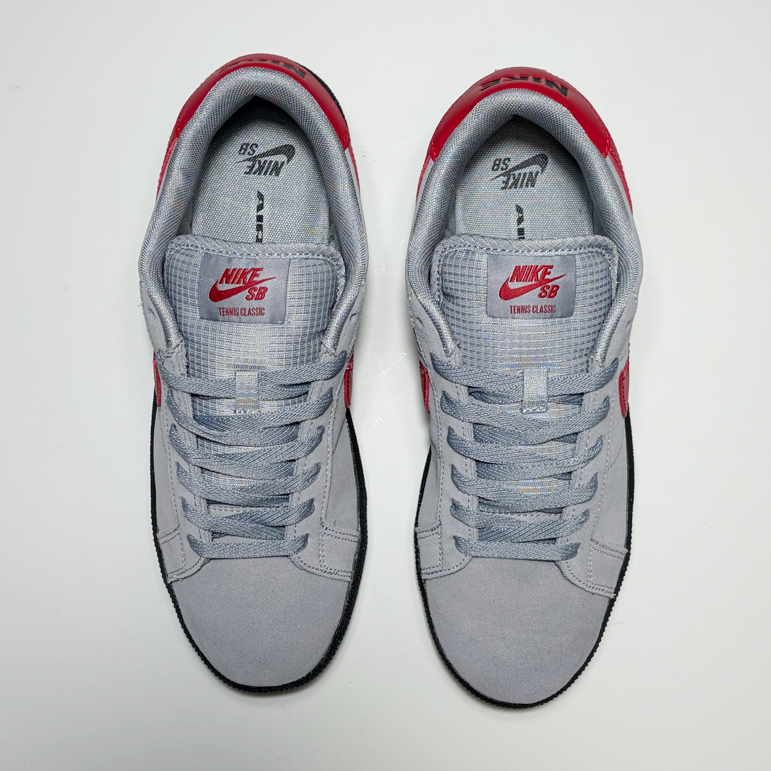 A pair of Nike SB Tennis Classic low-top sneakers in gray suede and mesh with red accents, shown from a top-down view on a light gray background.