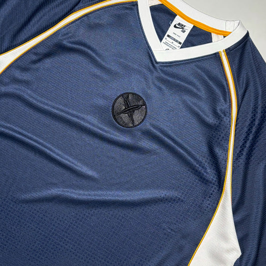 Close-up Nike SB Yuto Horigome navy blue athletic jersey with white and yellow trim, featuring a circular black logo on the chest.