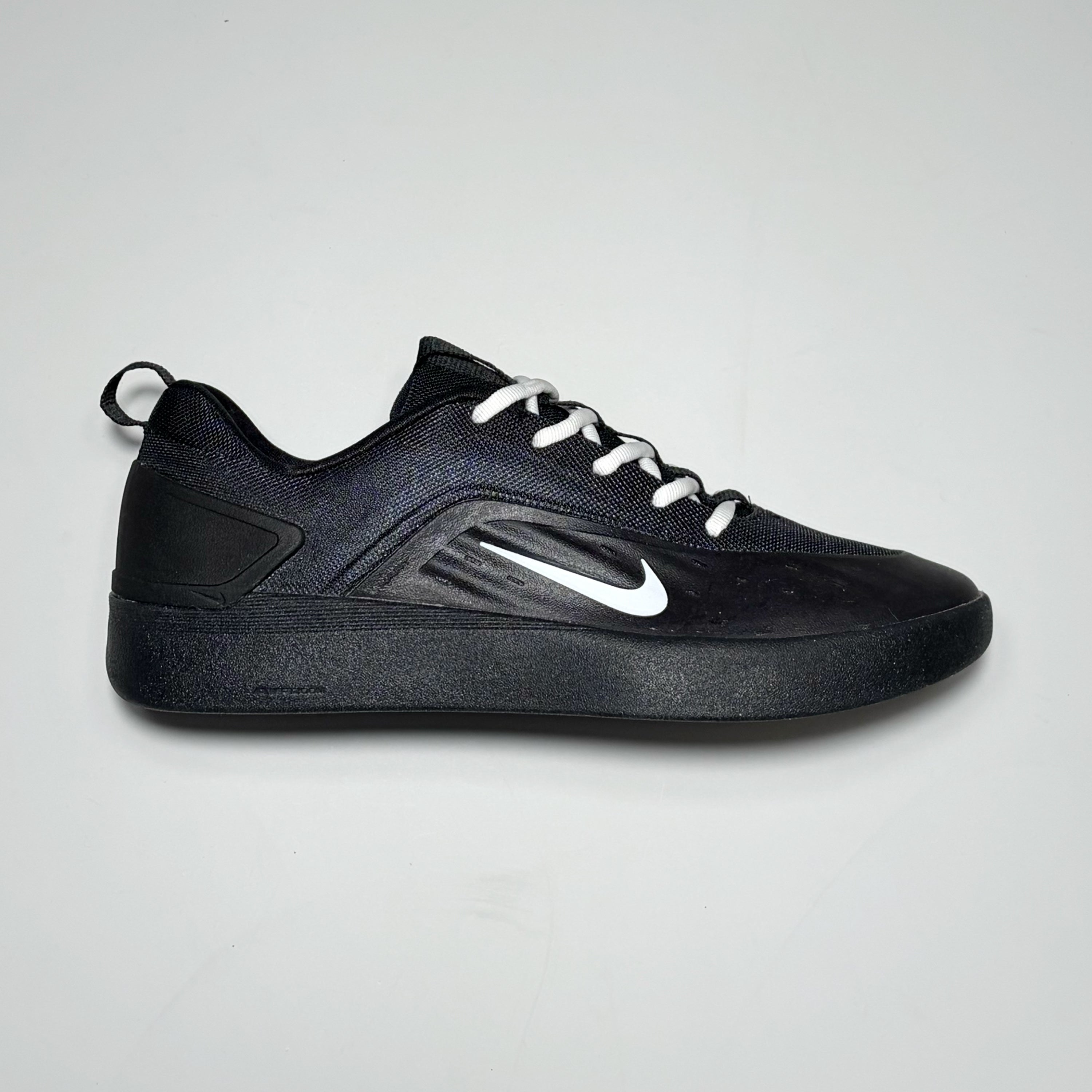 Side image of right shoe. Black nubuck with nylon and outsole. White swoosh logo.