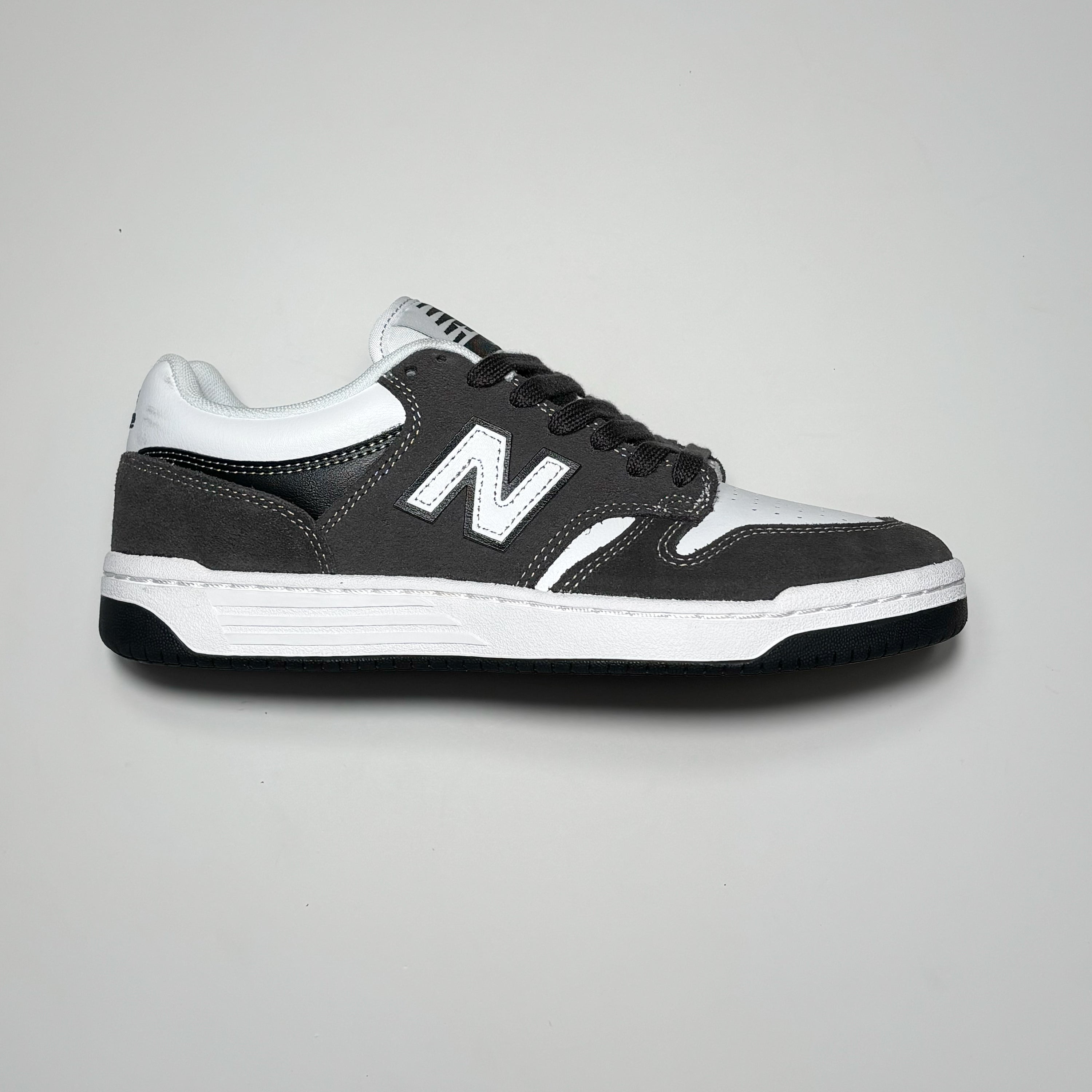 Side image of right shoe. Black cement suede panel with white contrast stitch.