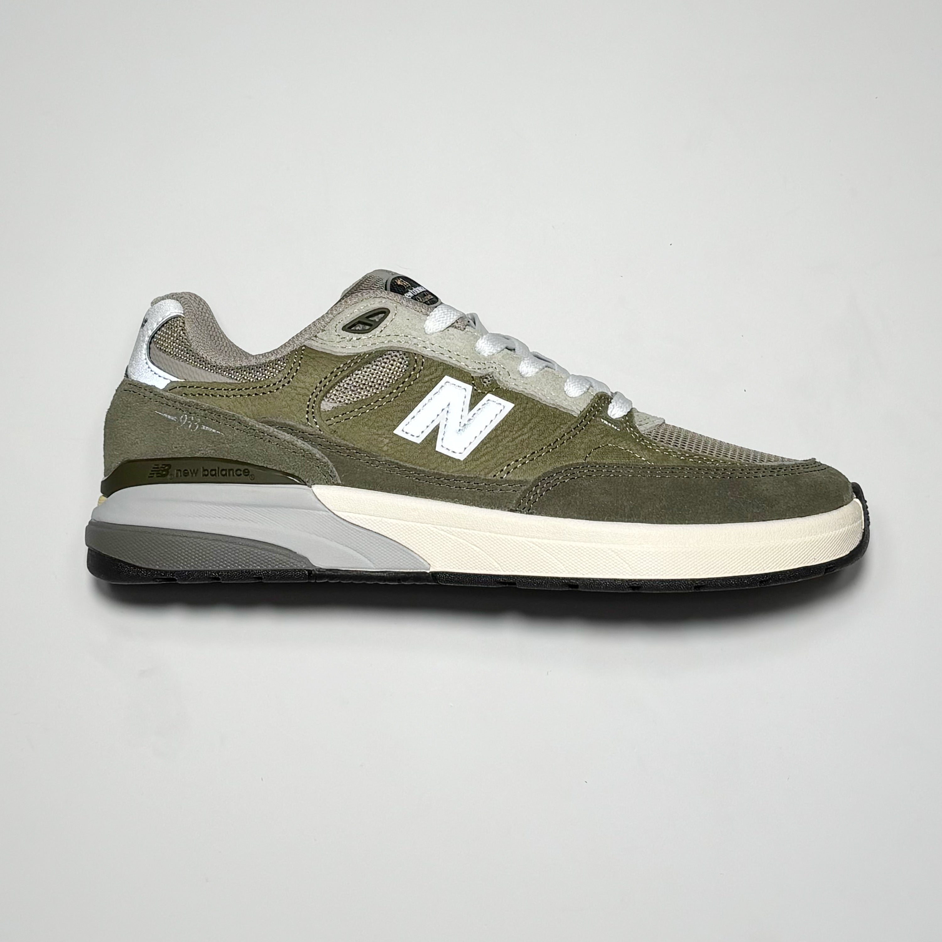 Side image of right shoe. Olive green suede with white N logo on mid-panel.