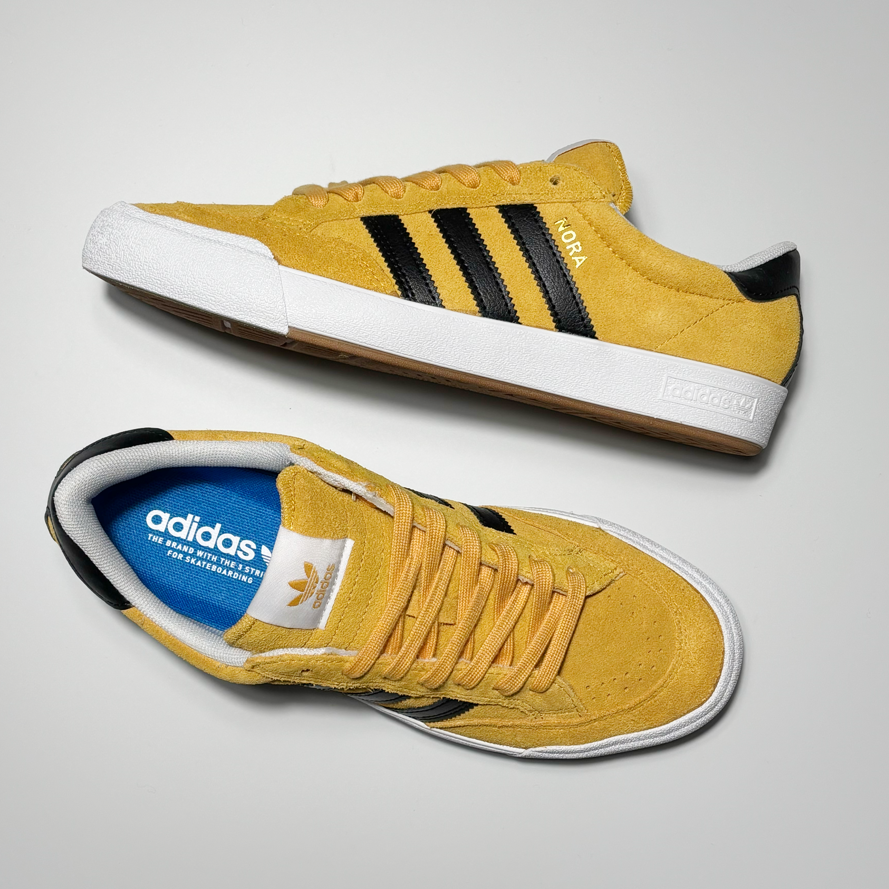 Toe down view with side profile.
White adidas label on tongue and nora in gold foil on heel panel.