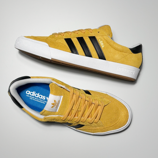 Toe down view with side profile.
White adidas label on tongue and nora in gold foil on heel panel.