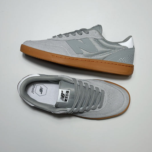 A pair of New Balance Numeric 440 Classic sneakers in gray suede and mesh with a white heel tab and a brown gum sole, shown from both top and side profiles on a light gray background.