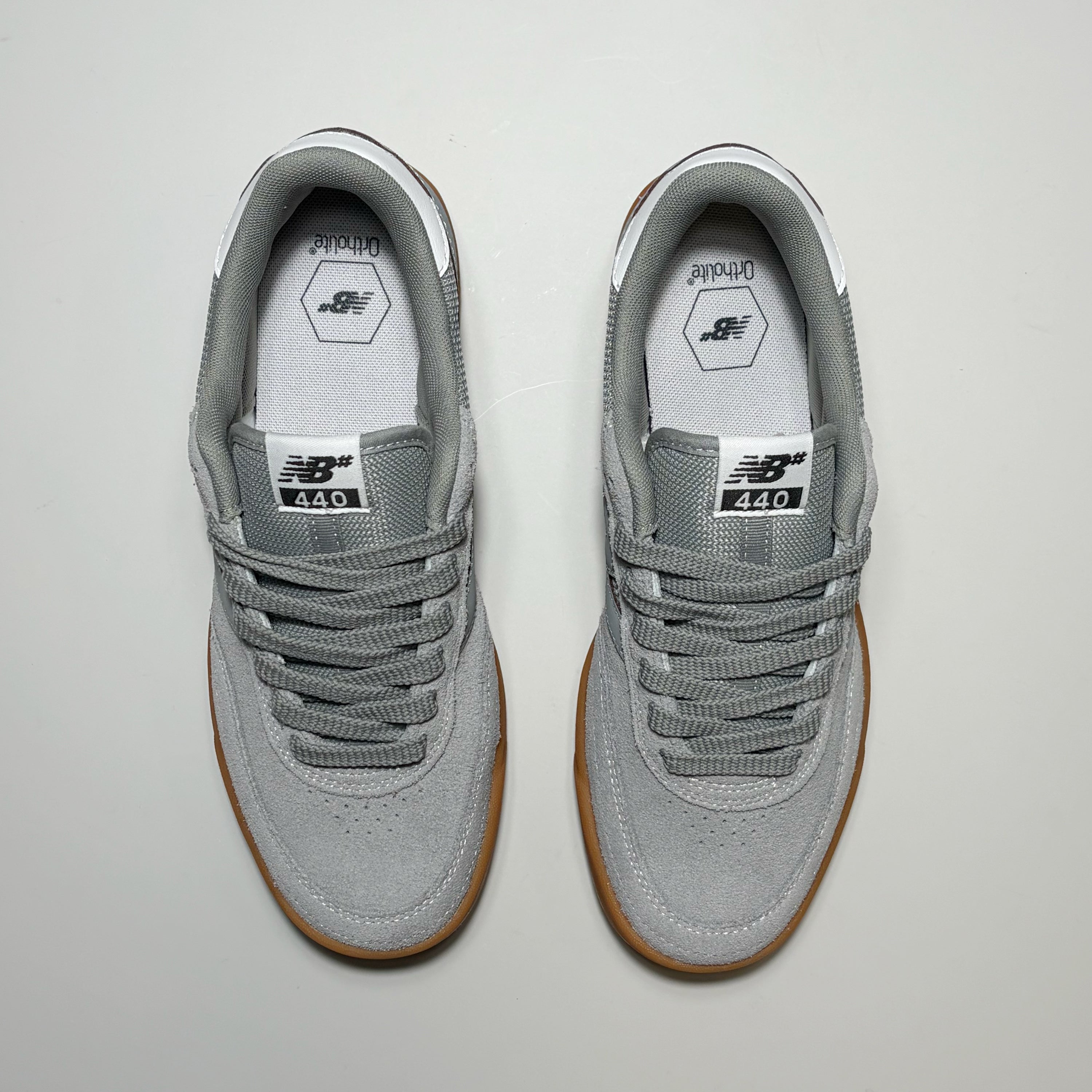 A pair of New Balance Numeric 440 V2 sneakers in gray suede and mesh, featuring brown gum soles, photographed from a top-down view on a light gray background.