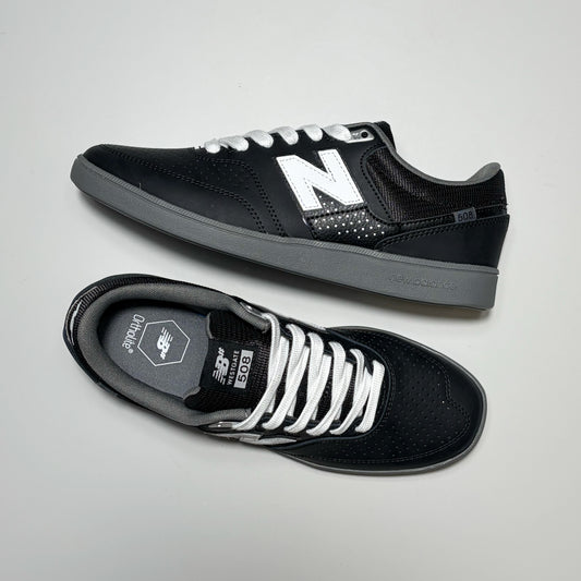 A pair of New Balance 508 sneakers, one on its side the other toe down view with white laces on grey background.