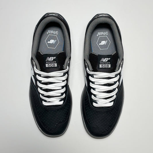 A pair of New Balance 508 Westgate signature sneakers shown from a top-down view. The shoes are primarily black with white laces, white side stripes, and a gray interior lining.