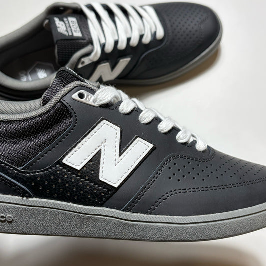 A pair of New Balance 508 sneakers in dark gray and black with white laces and a prominent white 'N' logo on the side, shown on a light gray background.