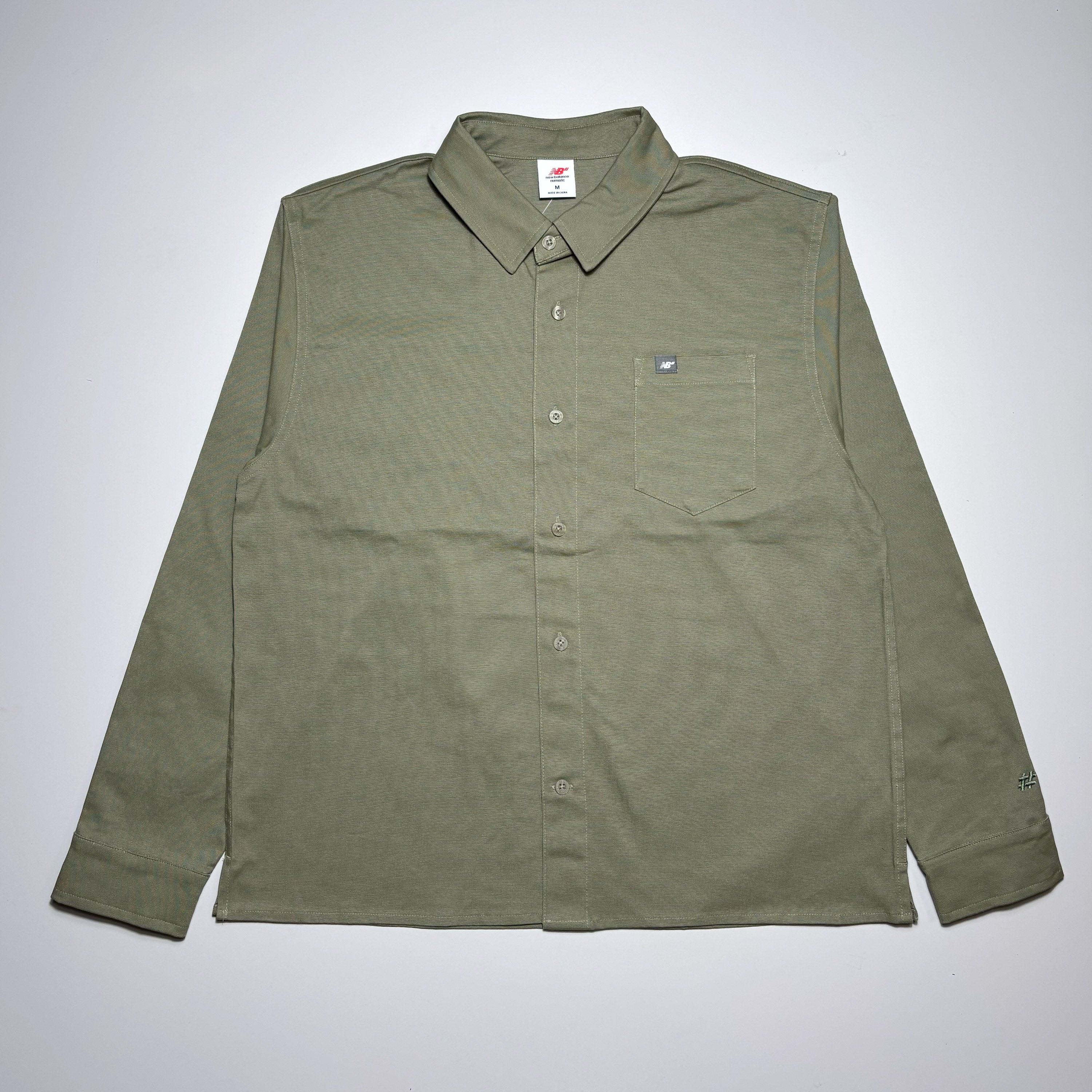 Full image of olive green canvas. 
Button closure and NB label on pocket.