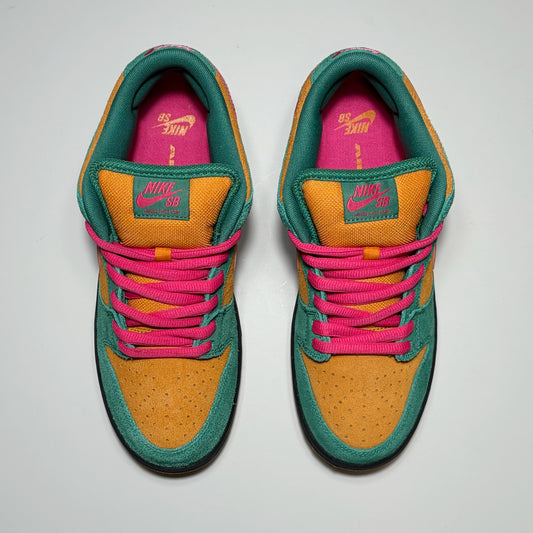 A pair of Nike SB Dunk Low sneakers shown from a top-down view on a light gray background. The shoes feature a mustard yellow suede toe box, teal green suede overlays, bright pink laces, and a vibrant pink interior lining with yellow Nike branding.