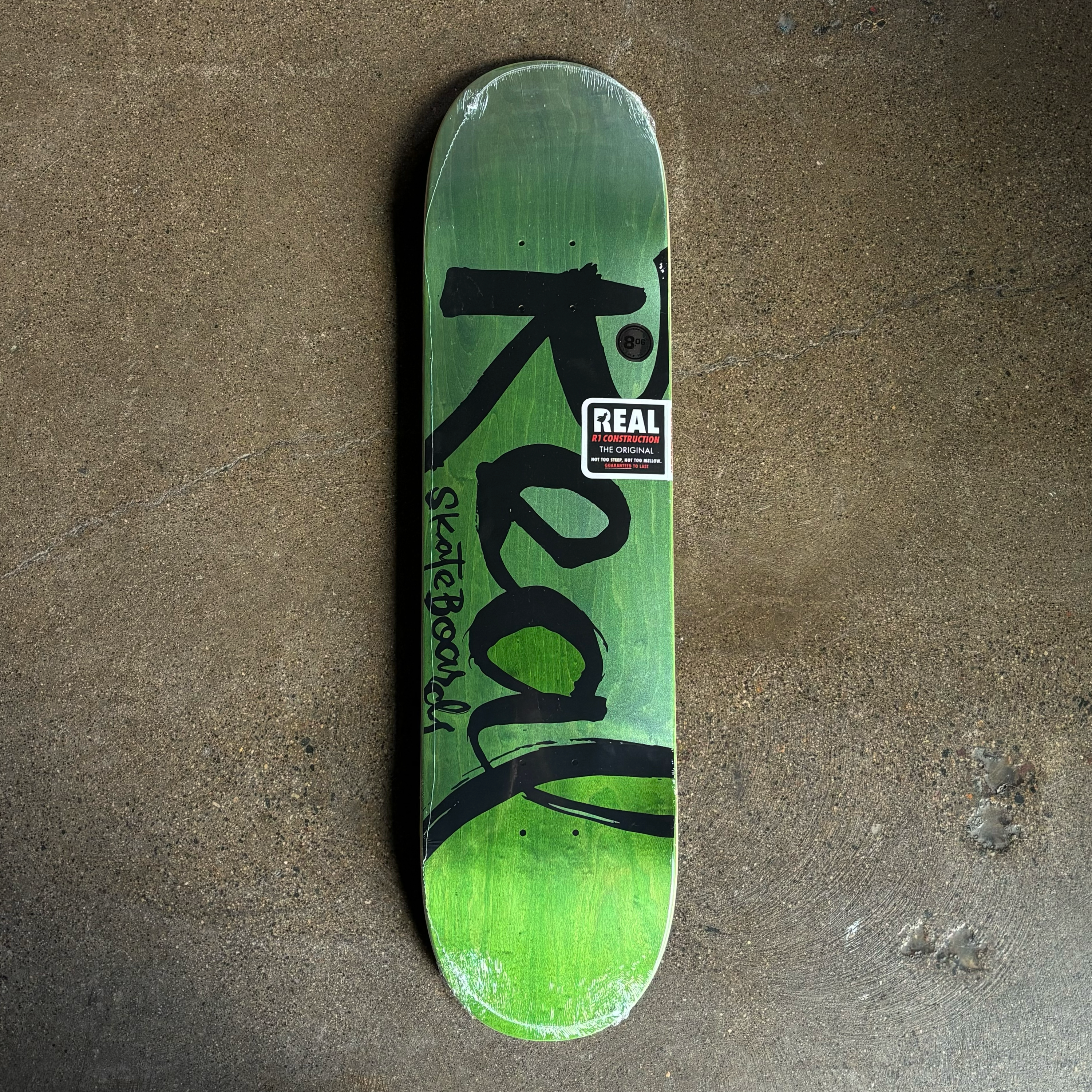 IMAGE OF ENTIRE DECK WITH REAL SKATEBOARDS FONT ON GREEN BACKGROUND