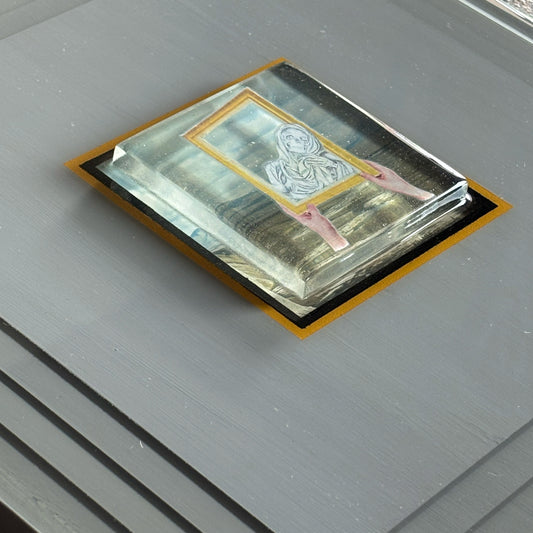 Center piece of art raised with collage artwork encased.